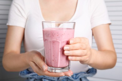 Photo of Woman holding glass of fresh raspberry smoothie, closeup