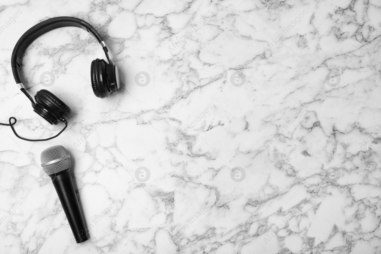 Photo of Headphones, microphone and space for text on marble background, top view