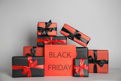 Many gift boxes and sheet of paper with words Black Friday on light grey background