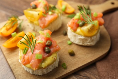Tasty canapes with salmon served on wooden table, closeup