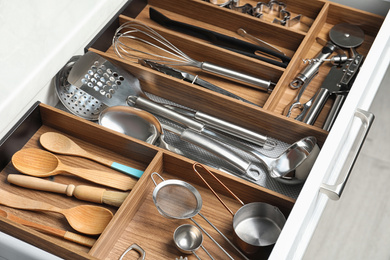 Photo of Different utensils in open desk drawer indoors, closeup