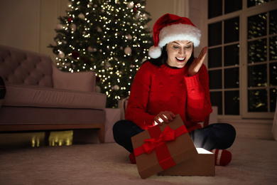 Photo of Emotional woman opening gift box in living room. Christmas celebration