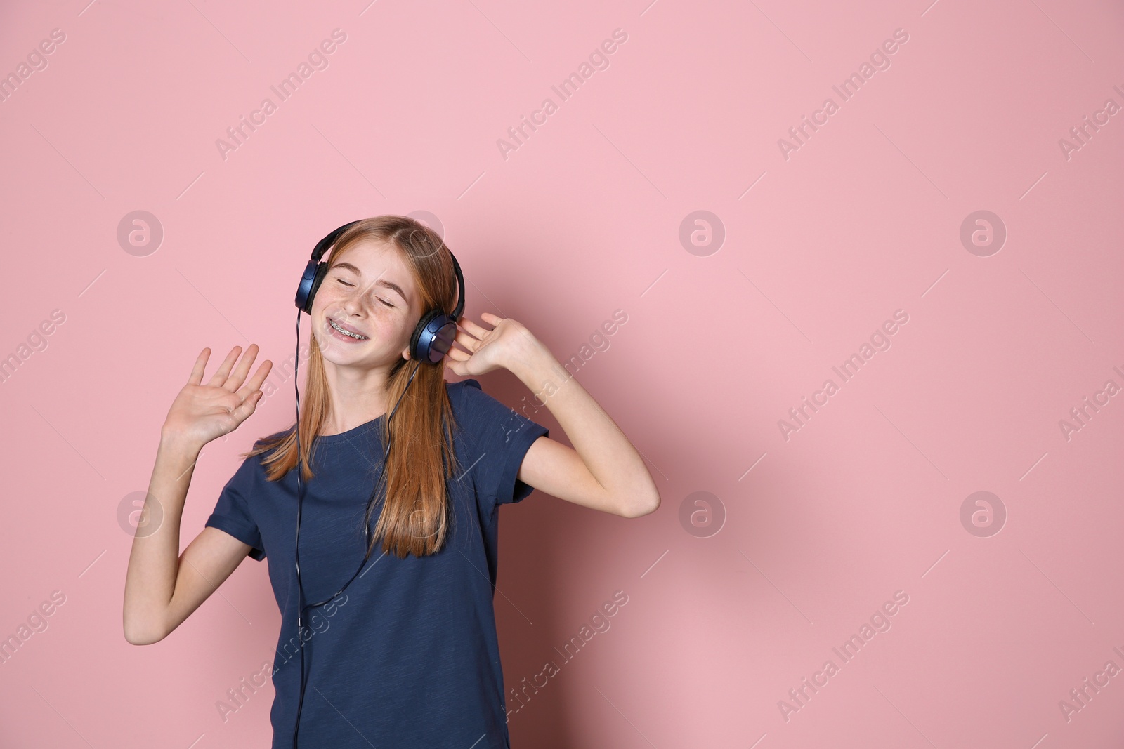 Photo of Teen girl listening to music with headphones on color background, space for text