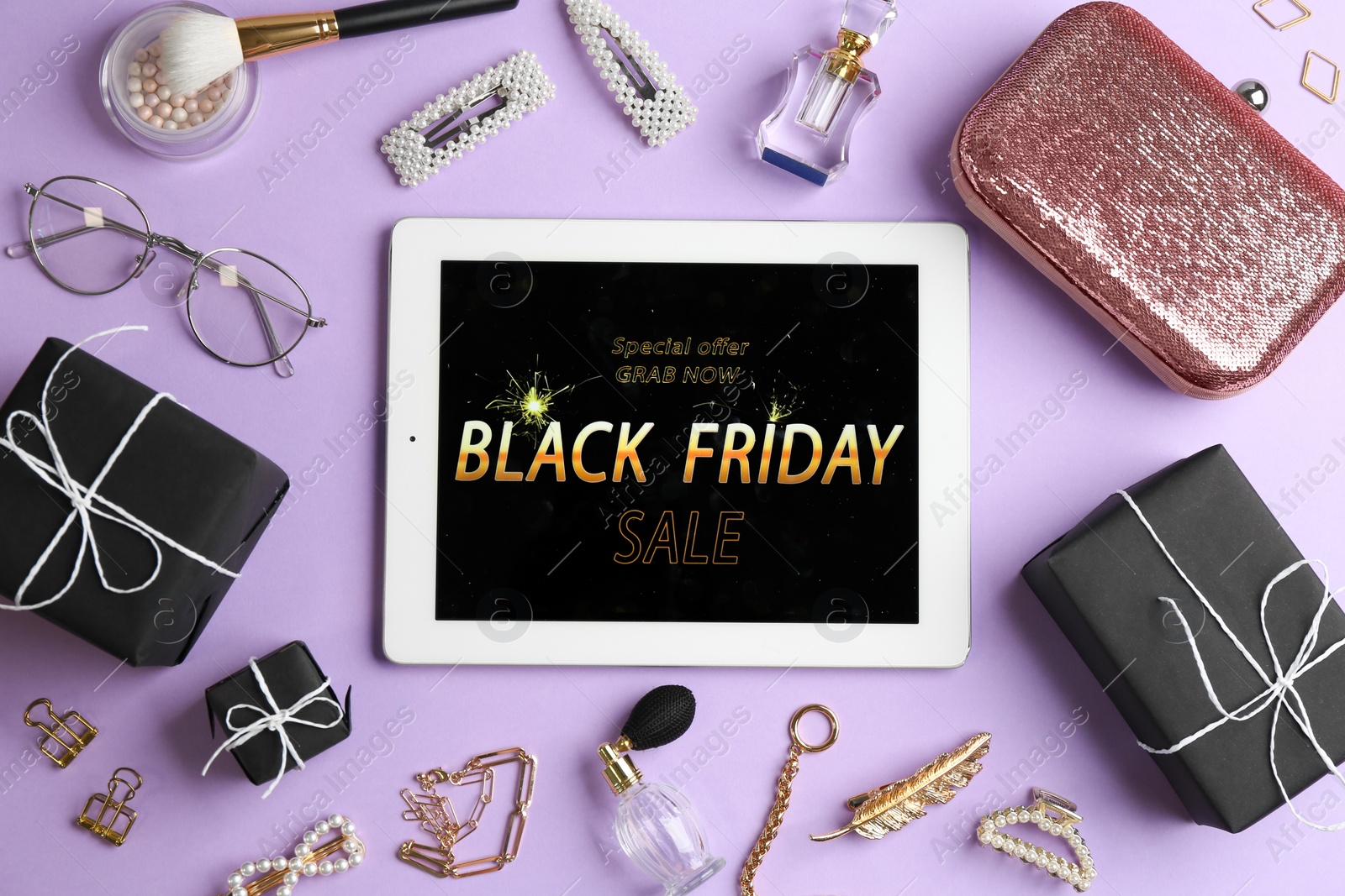 Photo of Flat lay composition with tablet, gifts and accessories on violet background. Black Friday sale