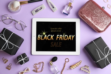 Photo of Flat lay composition with tablet, gifts and accessories on violet background. Black Friday sale