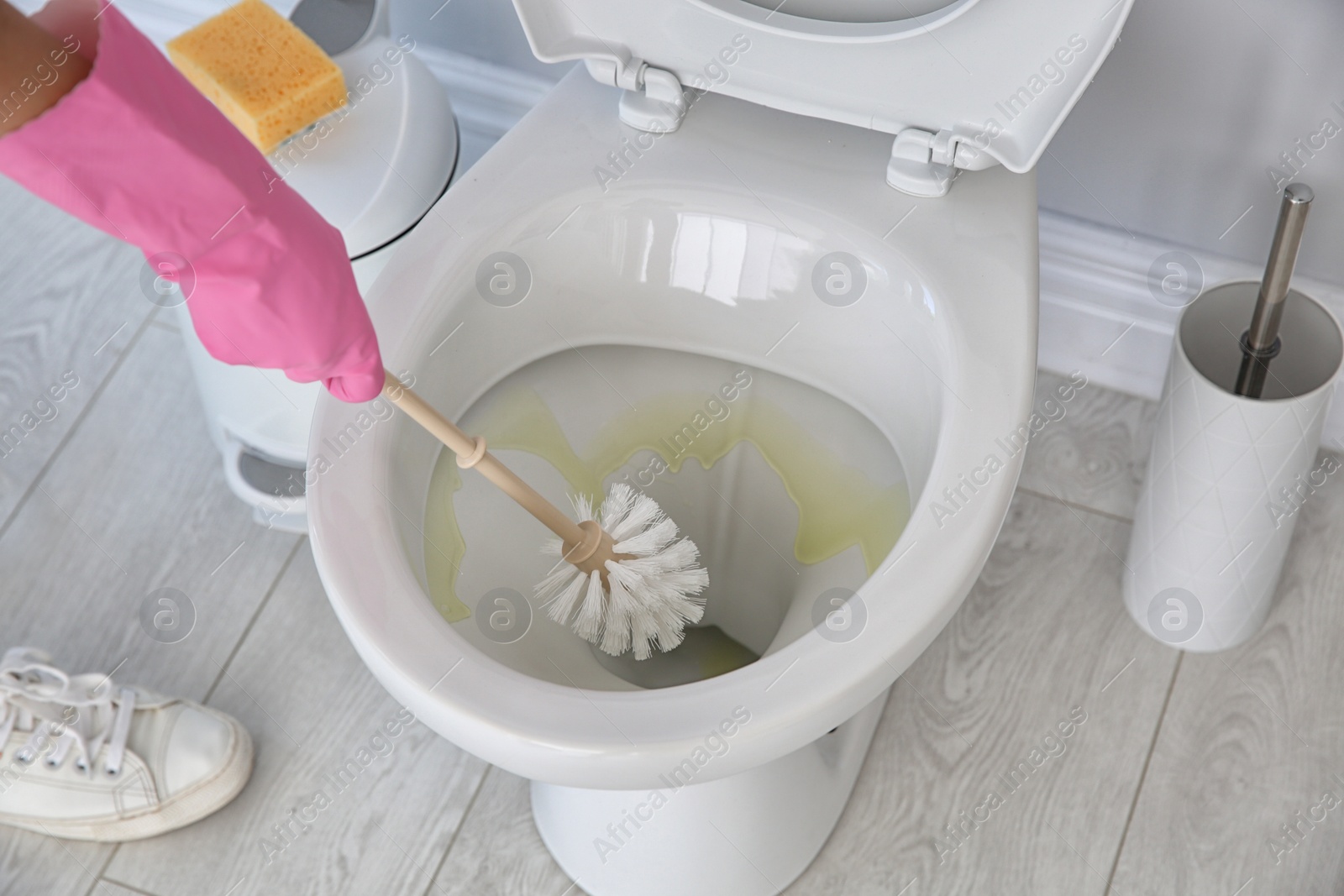 Photo of Woman cleaning toilet bowl in bathroom, closeup