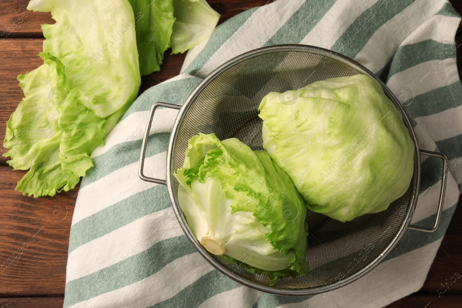 Photo of Fresh green clean iceberg lettuce heads and leaves on wooden table, flat lay