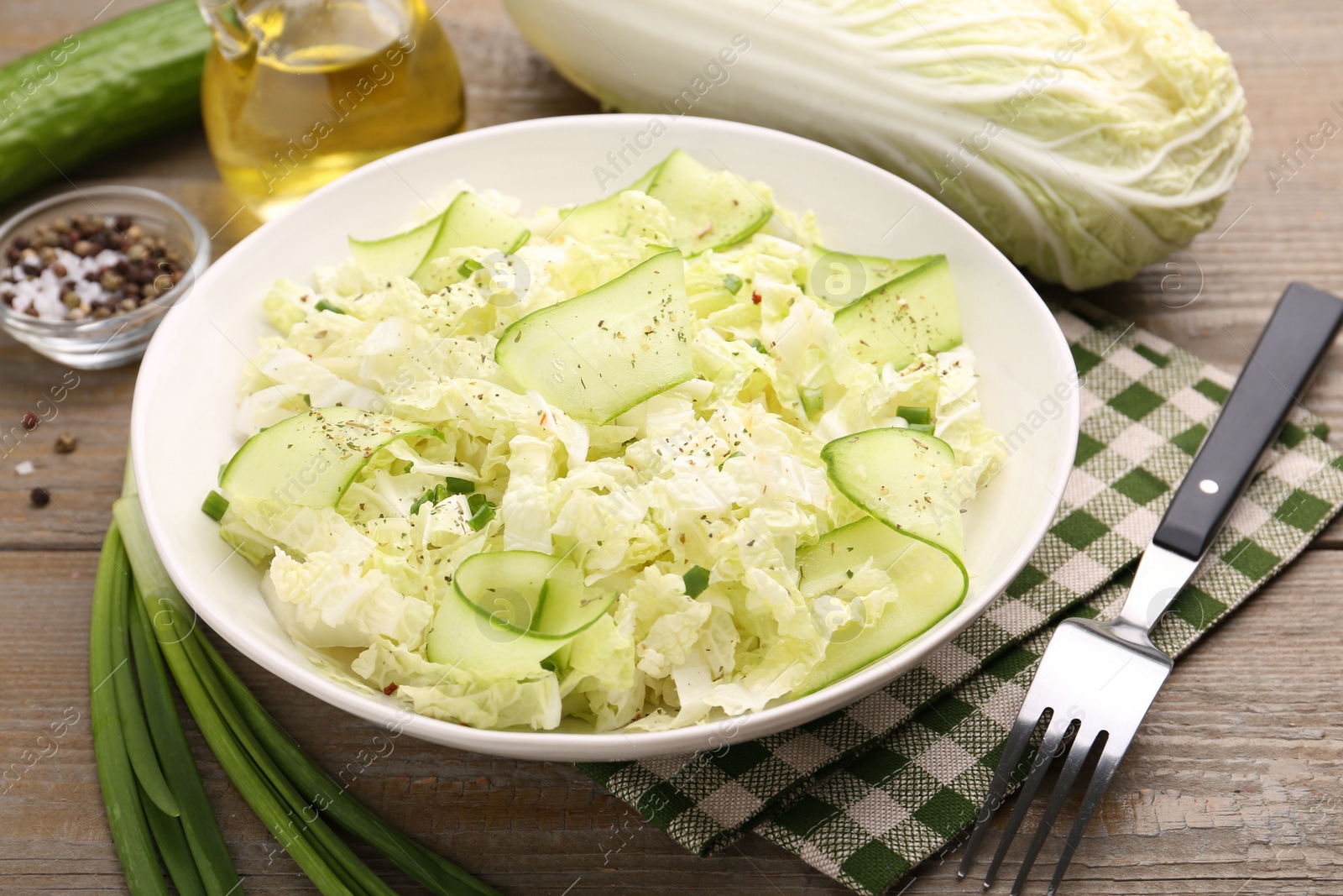 Photo of Tasty salad with Chinese cabbage, cucumber and green onion in bowl on wooden table, closeup