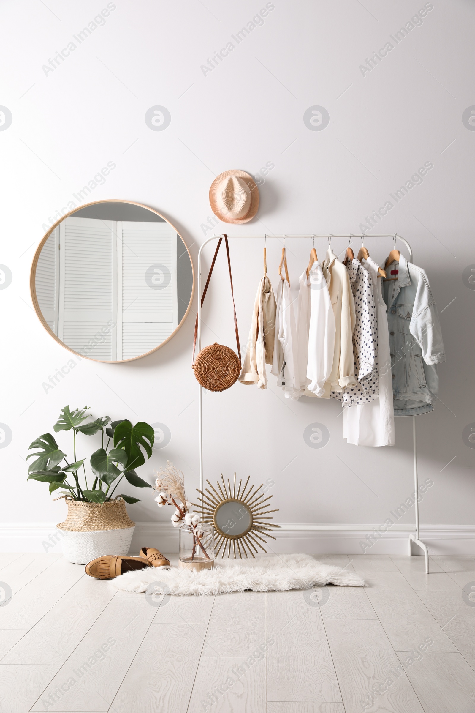 Photo of Rack with stylish women's clothes and mirror indoors. Interior design