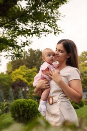 Happy mother with adorable baby walking in park on sunny day