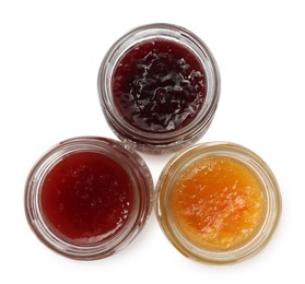 Jars with different jams on white background, top view