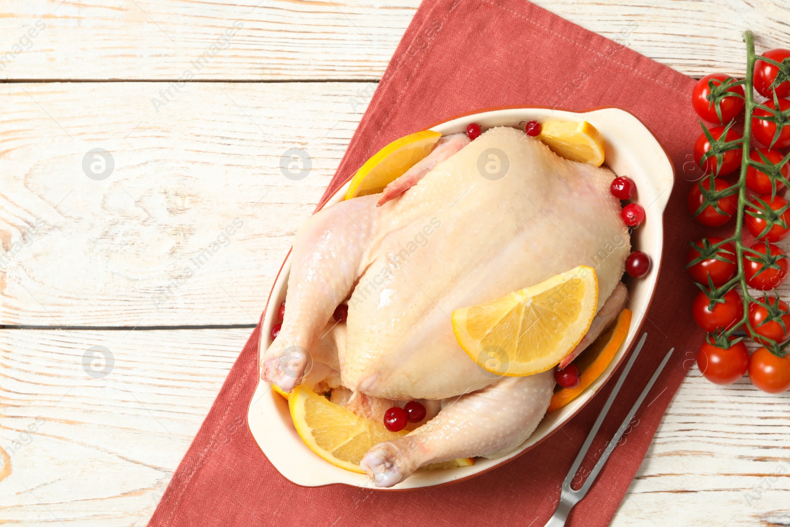 Photo of Chicken with orange slices, red berries and cherry tomatoes on white wooden table, flat lay