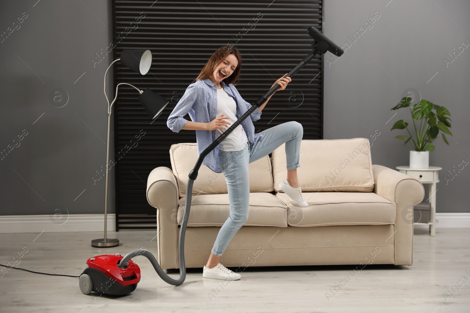 Photo of Young woman having fun while vacuuming at home