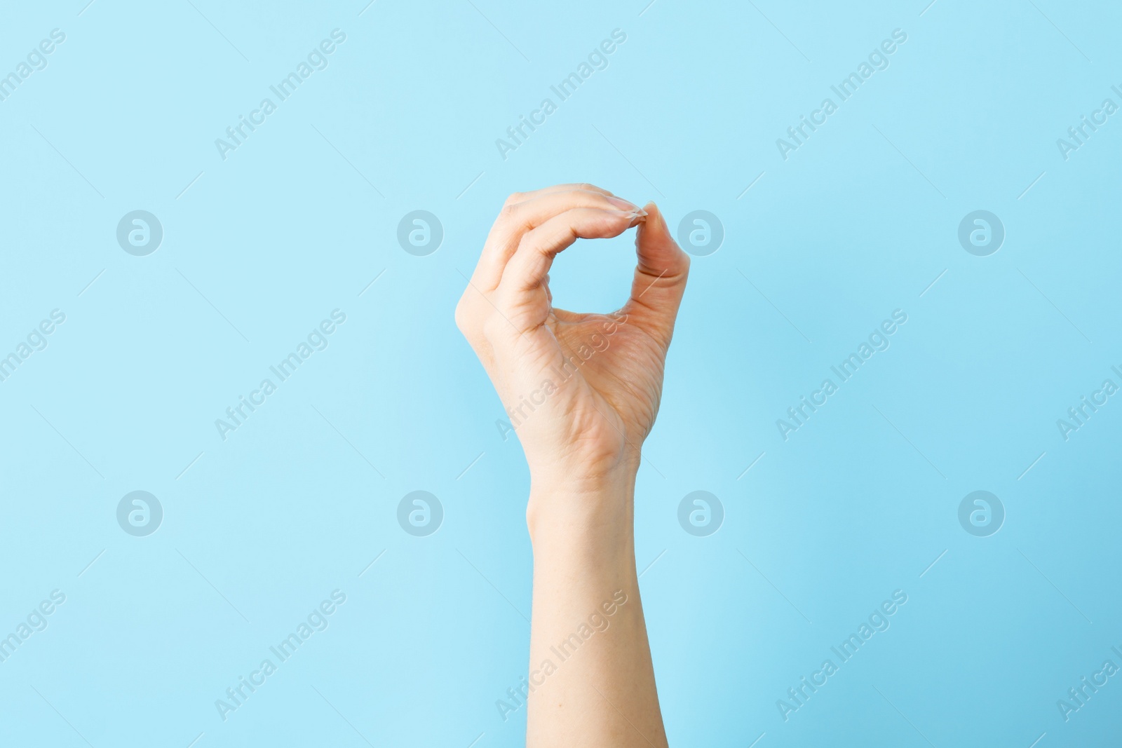 Photo of Woman showing O letter on color background, closeup. Sign language