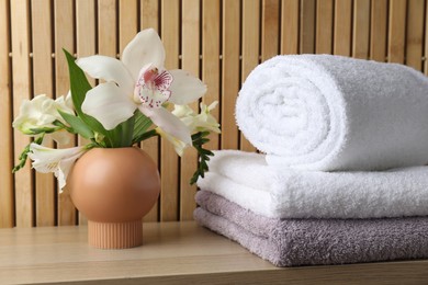 Photo of Terry towels and beautiful flowers on wooden table