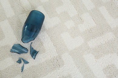 Broken blue glass vase on carpet, above view. Space for text