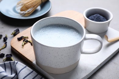 Blue matcha latte in cup on grey table