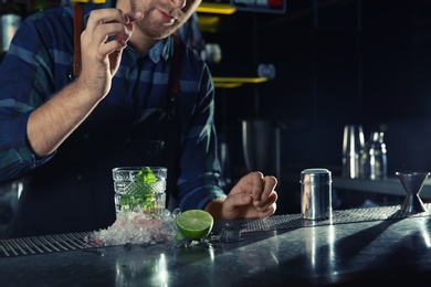 Photo of Barman making Mojito cocktail at counter in pub, closeup. Space for text