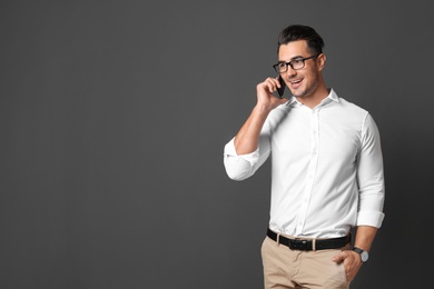 Photo of Handsome young man talking on phone against black background. Space for text