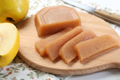 Tasty sweet quince paste, fresh fruits and knife on white wooden table, closeup