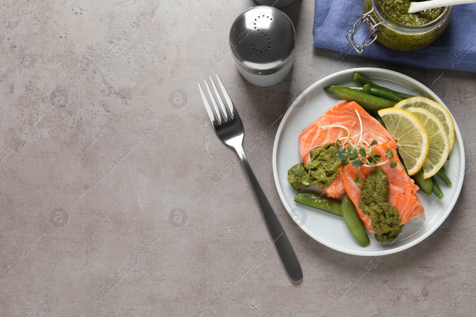 Photo of Tasty cooked salmon with pesto sauce served on grey table, flat lay. Space for text