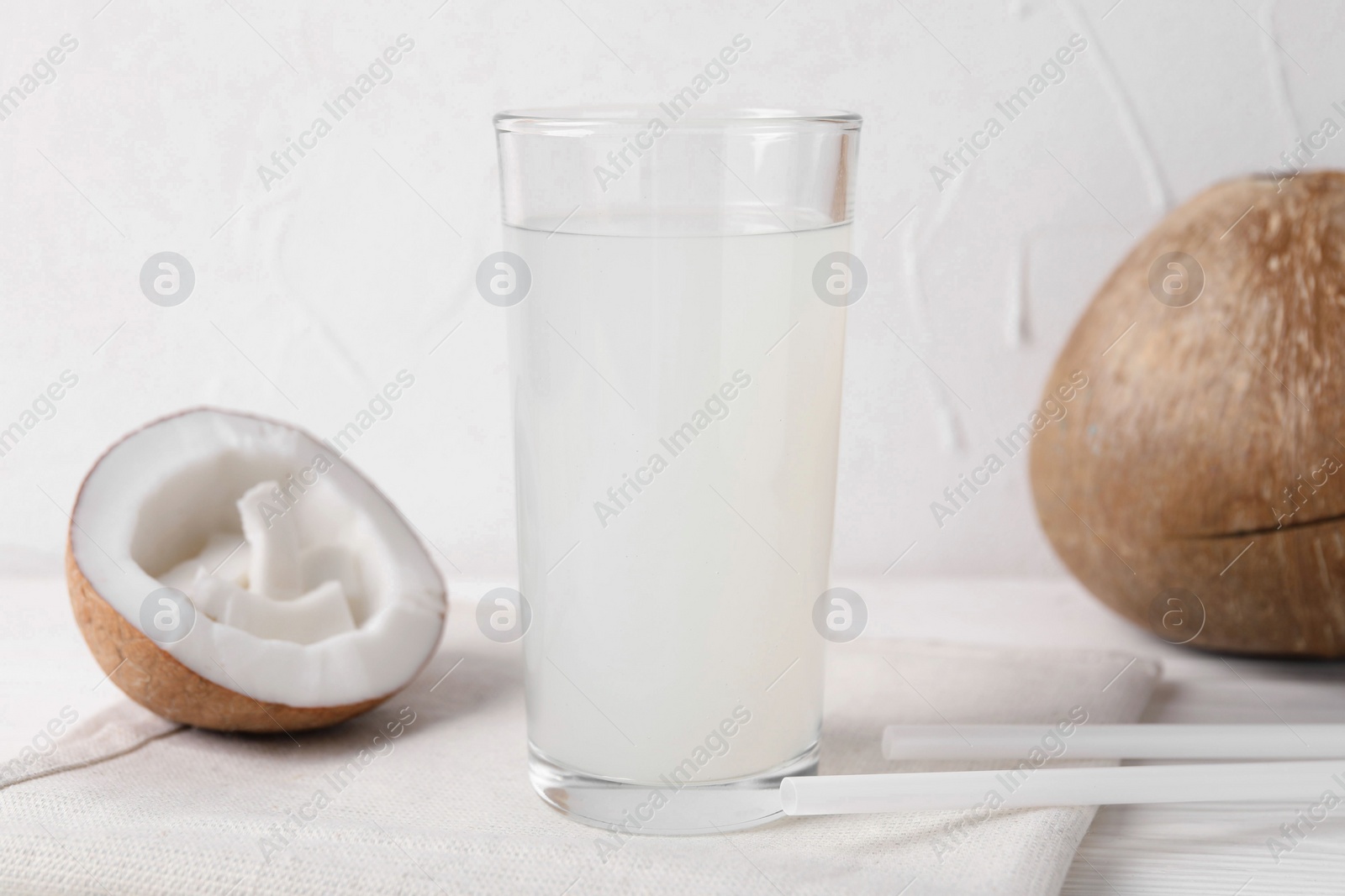 Photo of Glass of coconut water and nuts on white table