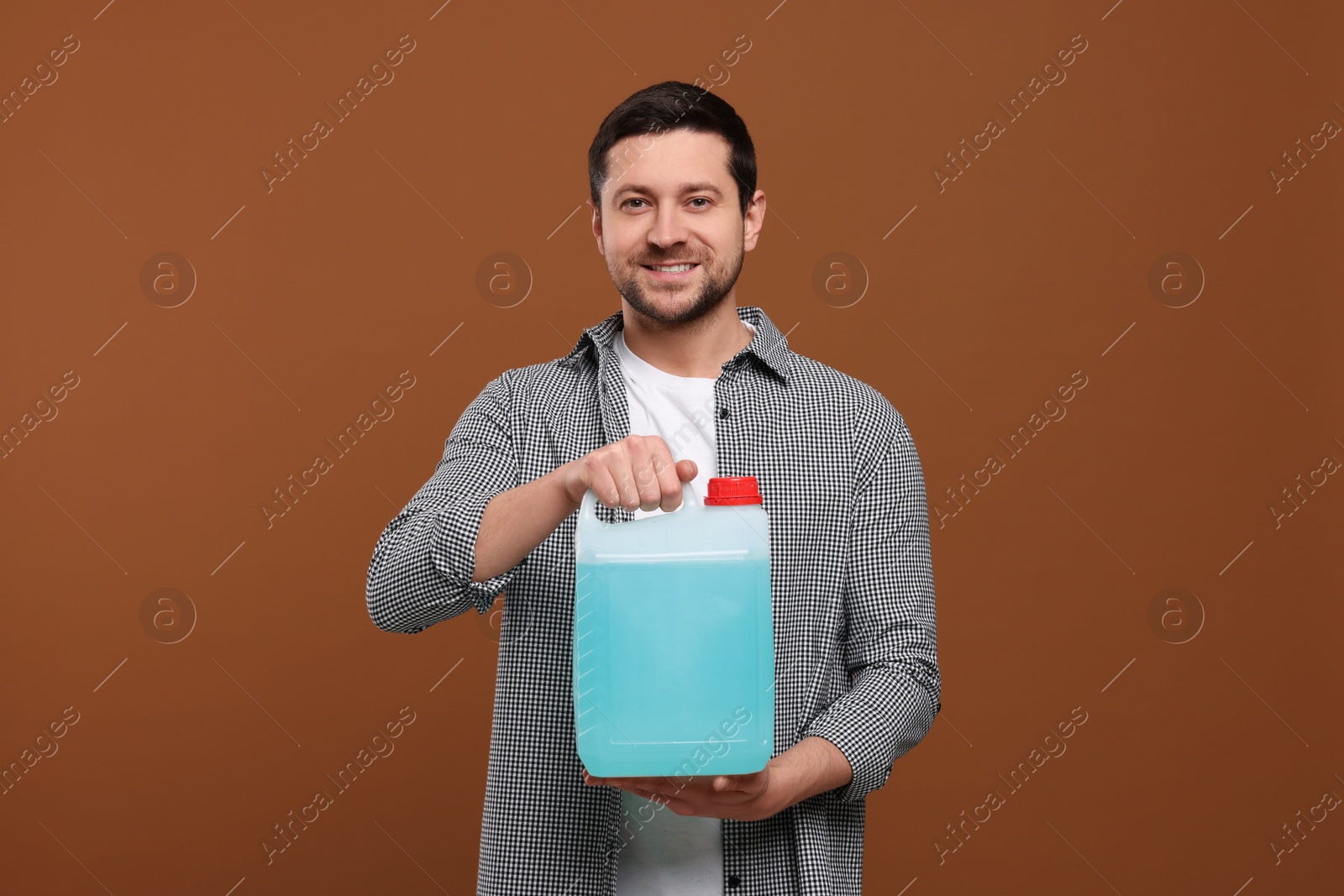 Photo of Man holding canister with blue liquid on brown background