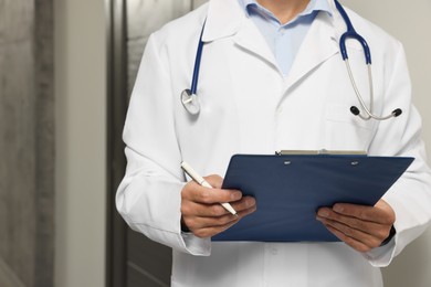 Photo of Doctor in white coat with stethoscope and clipboard indoors, closeup