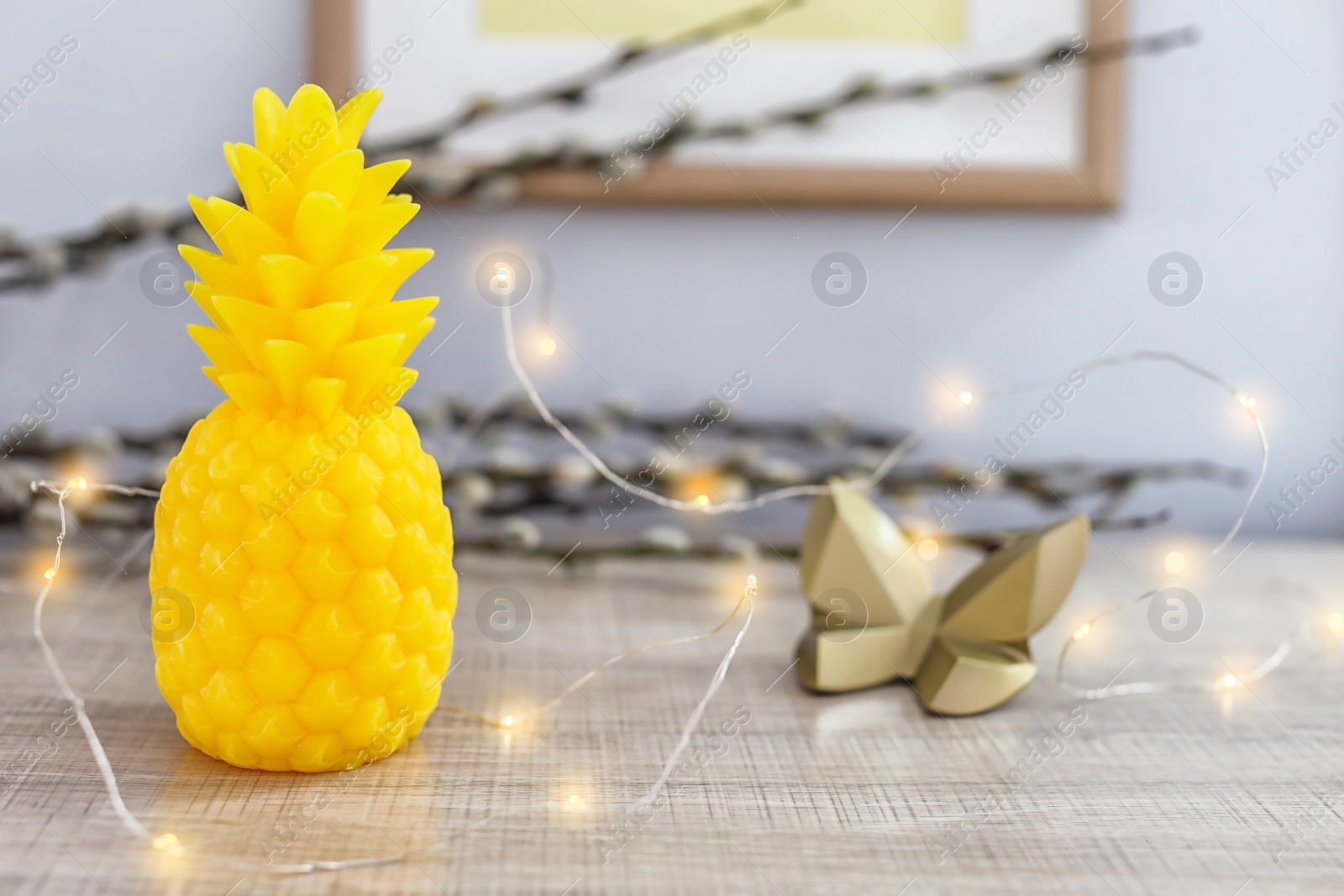 Photo of Pineapple shaped candle and electric garland on table