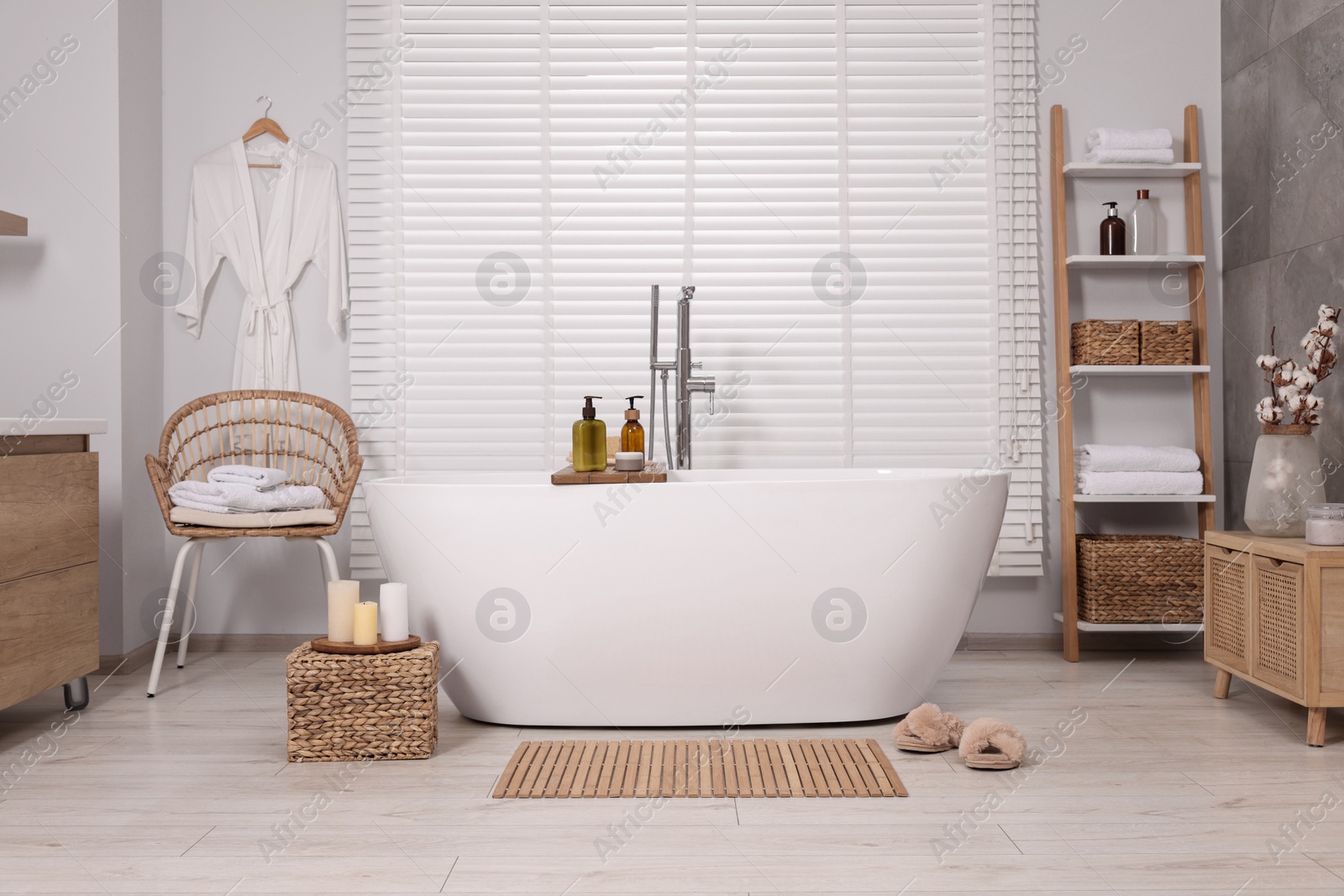 Photo of Stylish bathroom interior with bamboo bath mat and white tub