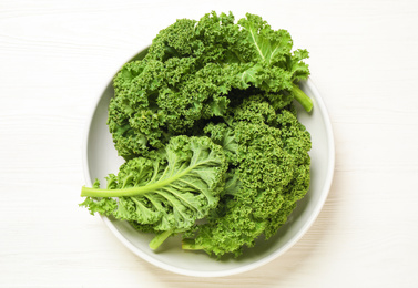 Photo of Fresh kale leaves on white wooden table, top view