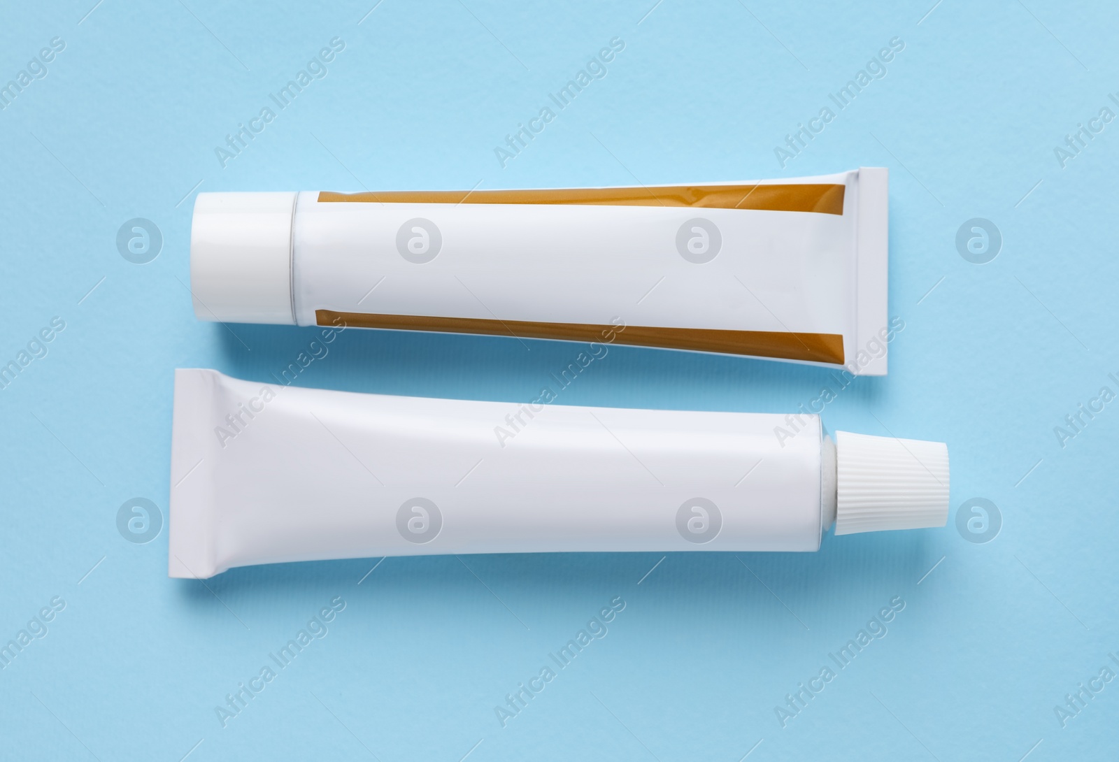 Photo of Tubes of ointment on light blue background, flat lay. Space for text