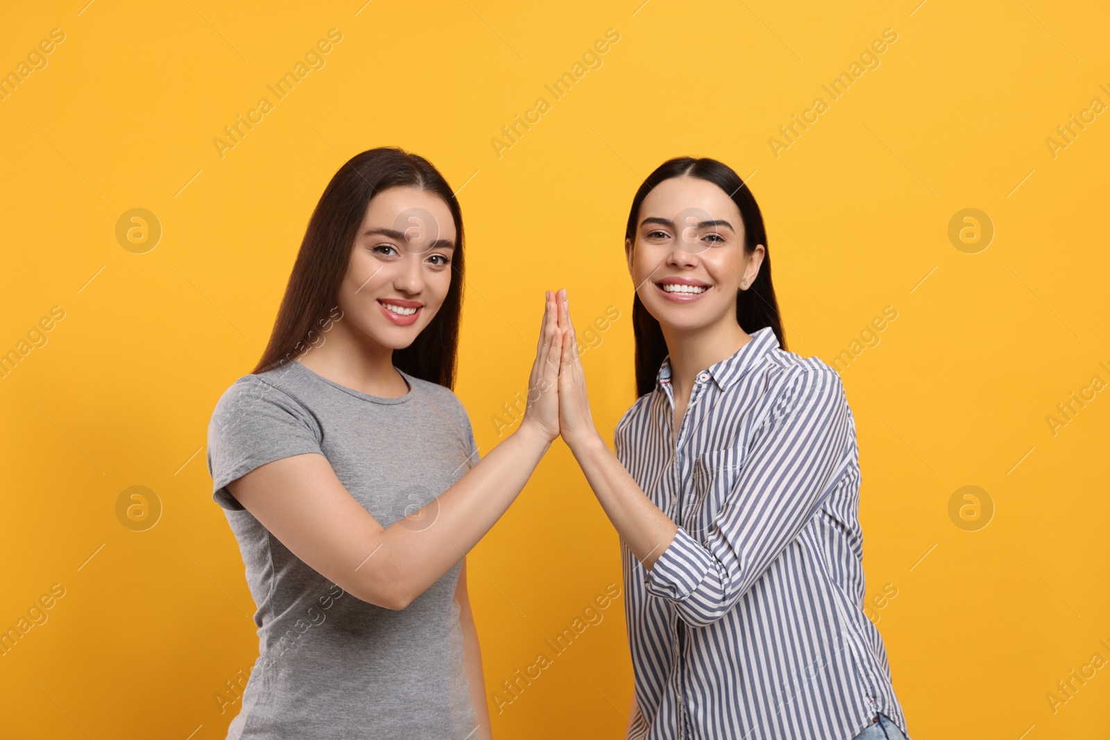 Photo of Women giving high five on orange background