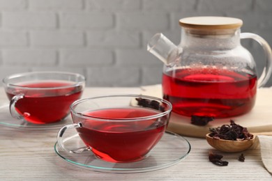 Photo of Fresh hibiscus tea and dry flower leaves on wooden table