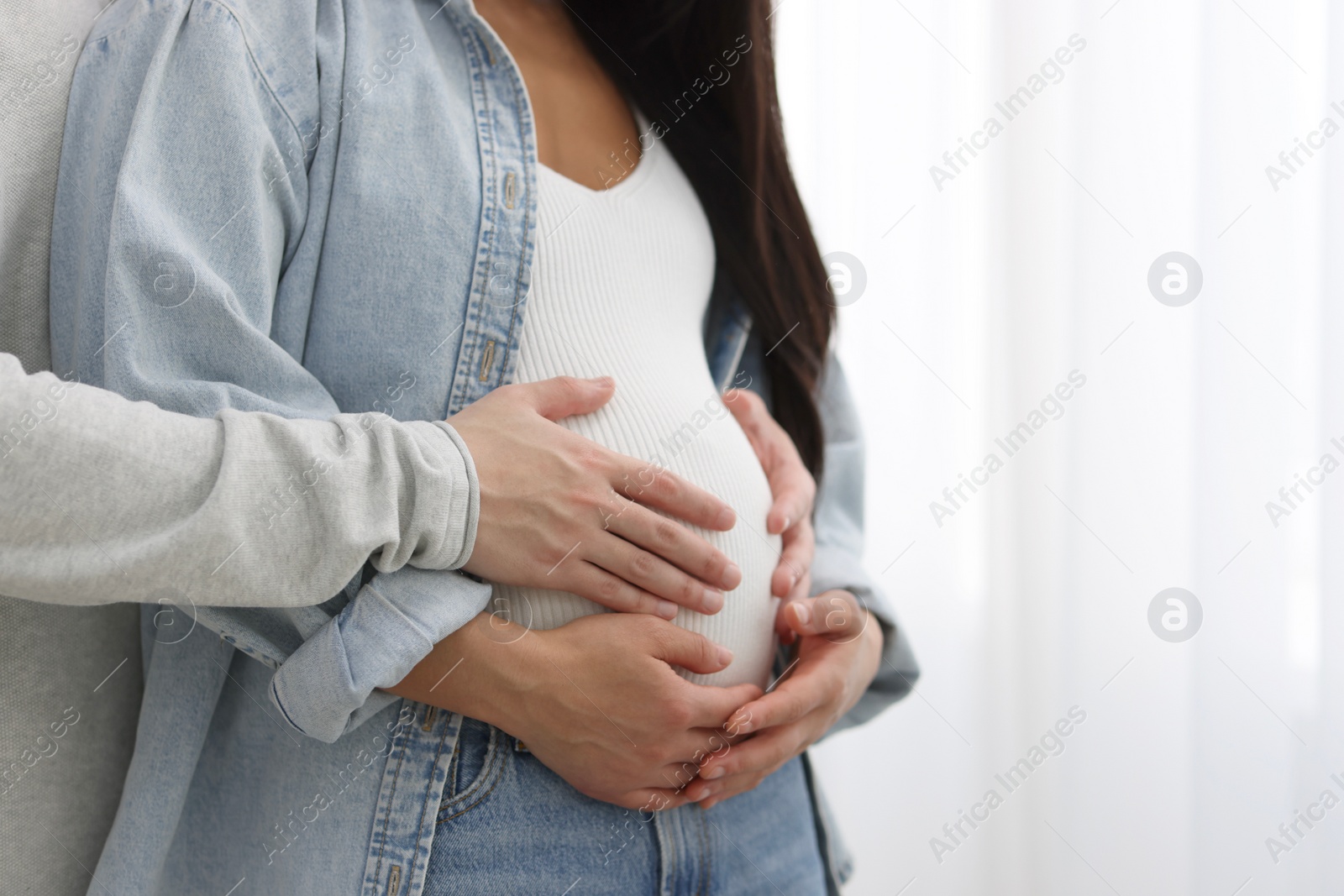 Photo of Man touching his pregnant wife's belly at home, closeup. Space for text