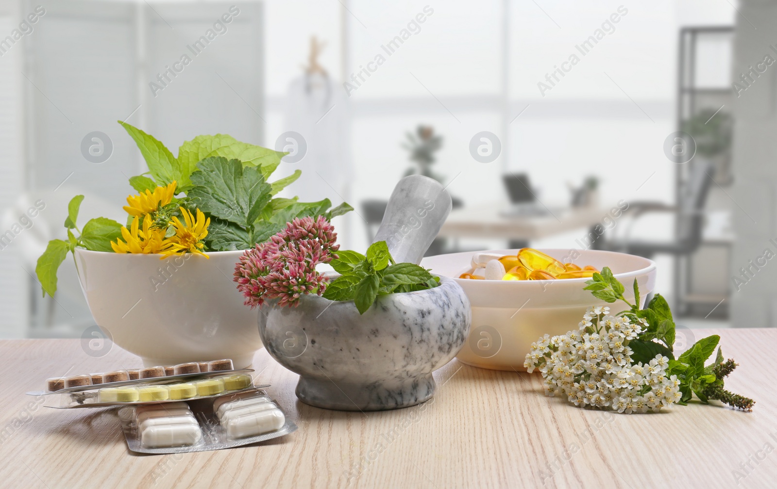 Image of Mortar with fresh herbs and pills on wooden table in medical office