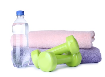 Photo of Stylish dumbbells, bottle of water and towels on white background. Home fitness