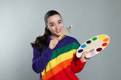 Photo of Woman with painting tools on grey background. Young artist