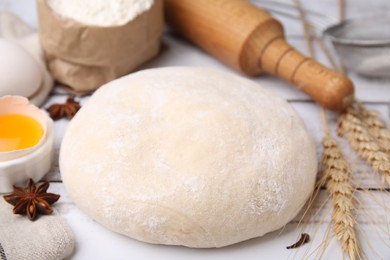 Fresh dough and ingredients on white wooden table, closeup