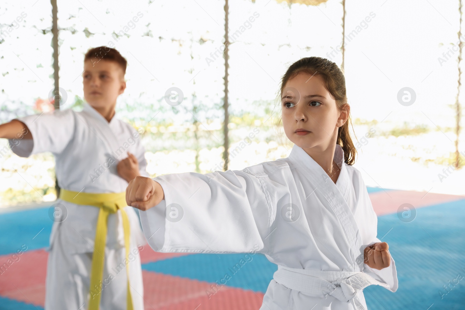 Photo of Children in kimono practicing karate on tatami outdoors