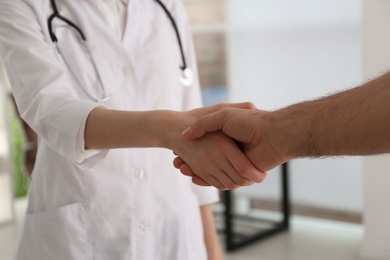 Doctor and patient shaking hands in clinic, closeup