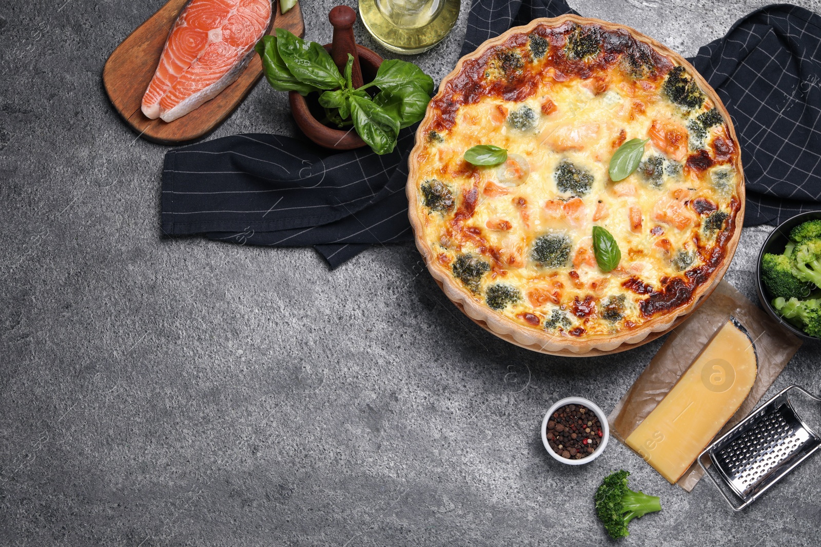 Photo of Delicious homemade quiche and ingredients on gray table, flat lay. Space for text