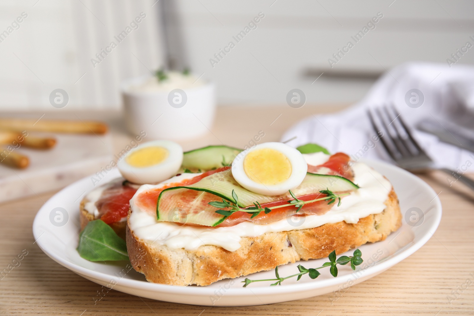 Photo of Plate of delicious bruschettas with salmon on wooden table in kitchen