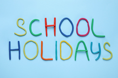 Phrase School Holidays made of modeling clay on light blue background, top view