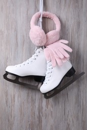 Pair of ice skates, warm earmuffs and gloves hanging on wooden wall