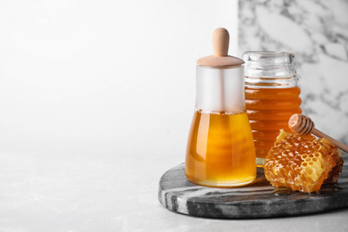 Photo of Tasty organic honey on light grey table, space for text