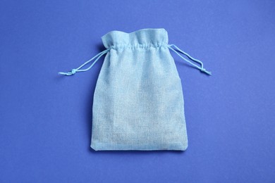 Burlap bag on blue background, top view