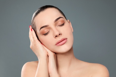 Photo of Portrait of young woman with beautiful face and natural makeup on color background