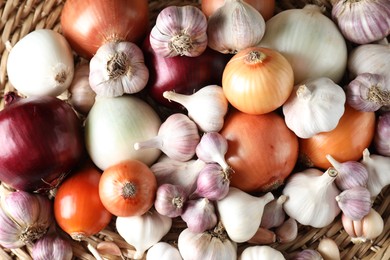 Photo of Fresh raw garlic and onions in wicker basket, top view