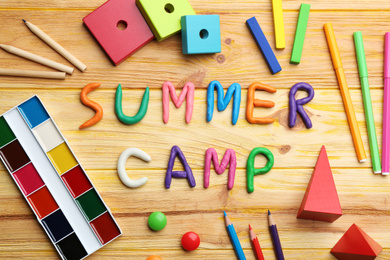 Flat lay composition with phrase SUMMER CAMP made of modelling clay on wooden background